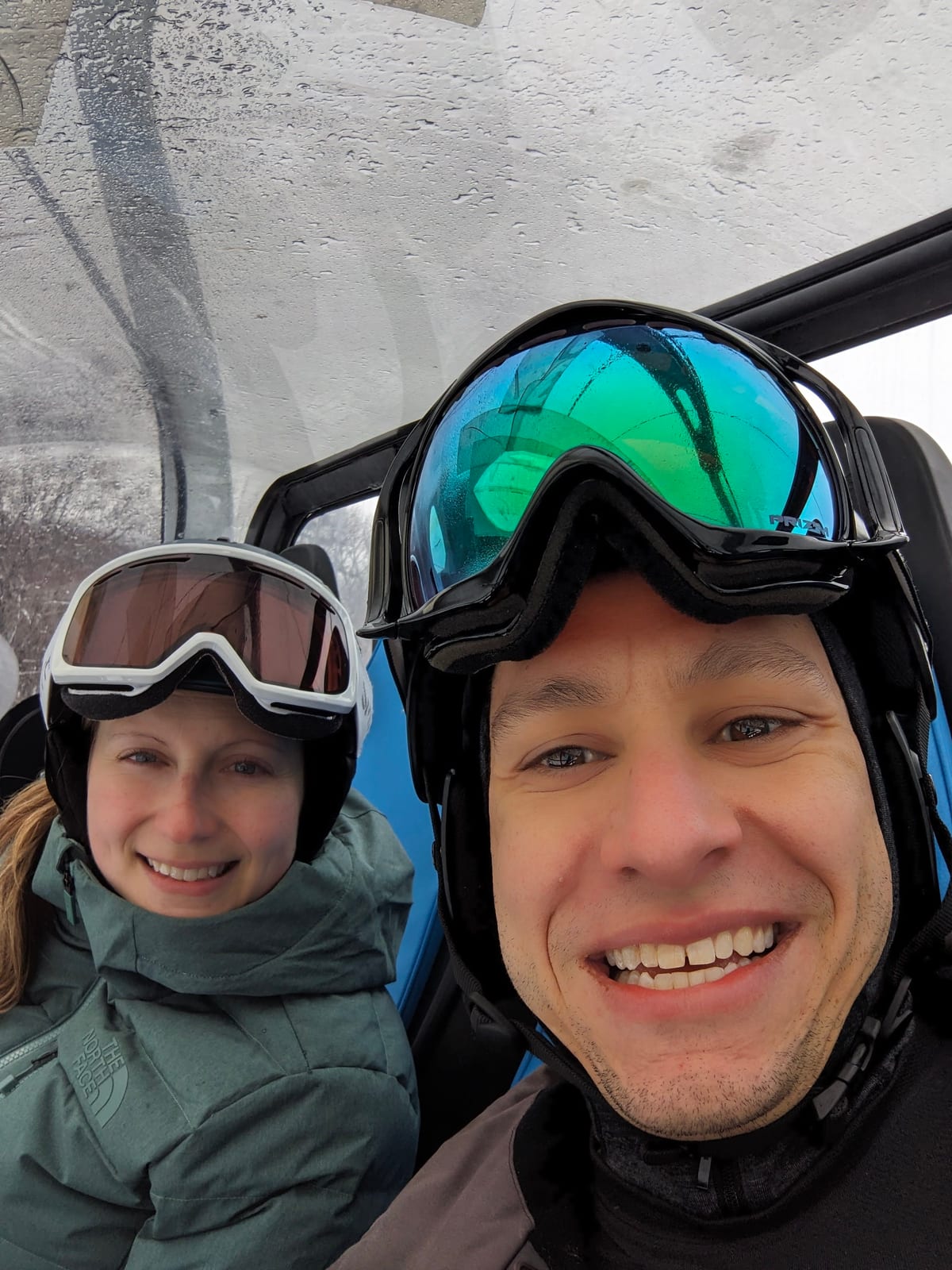 Brett Musco and Amanda smiling in ski gear on a chairlift